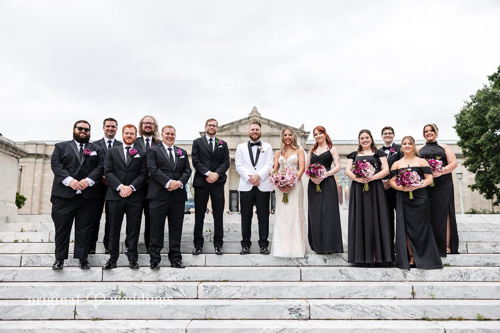 Dan + Alex A large group of wedding guests posing together around a bride and groom.