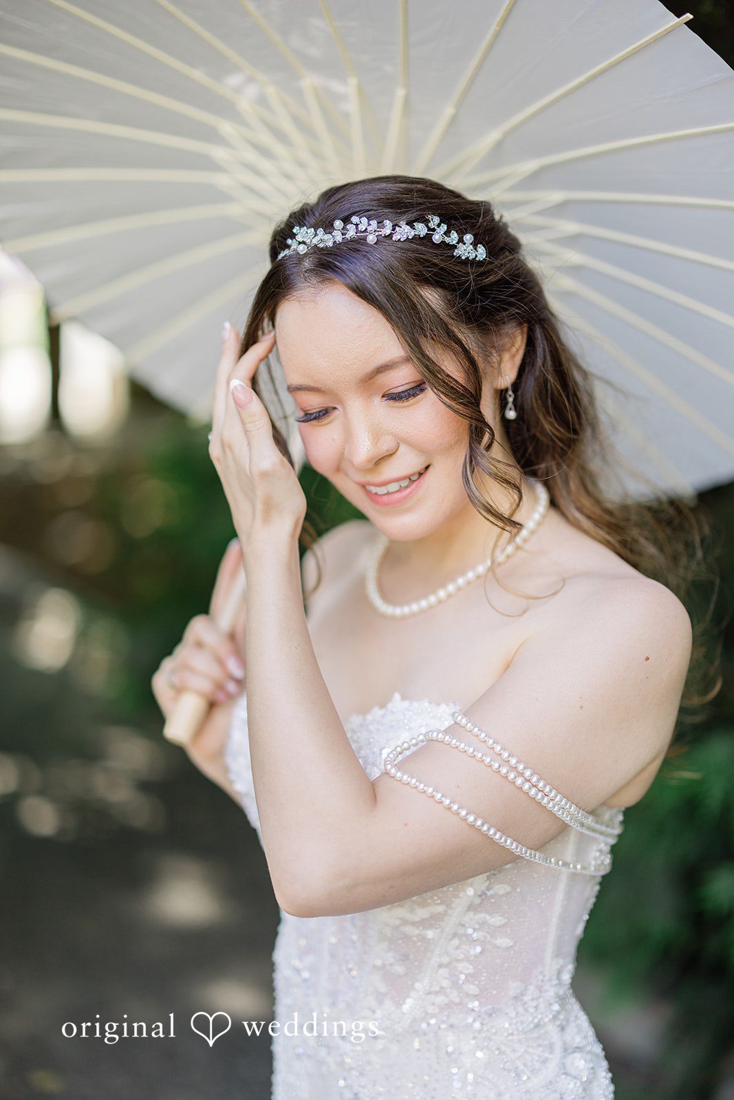 Veronica + Andrew A bride holding a white parasol while smiling and looking down.