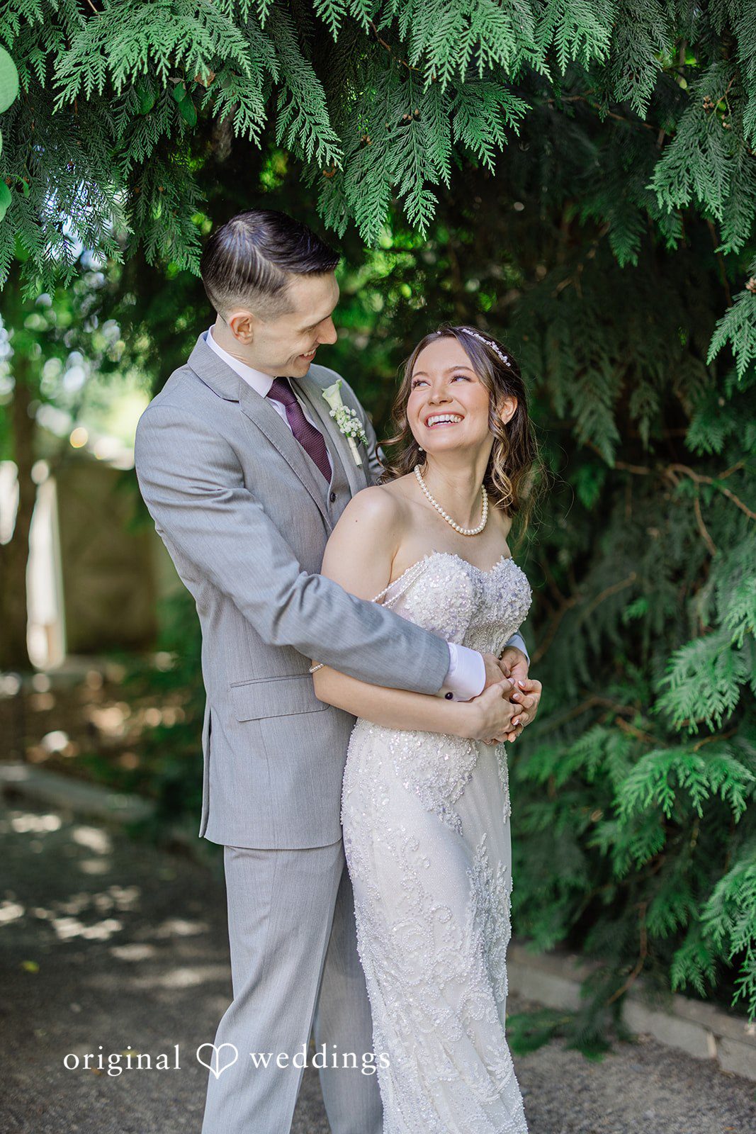 Veronica + Andrew A groom wraps his arms around the bride from behind as they smile.