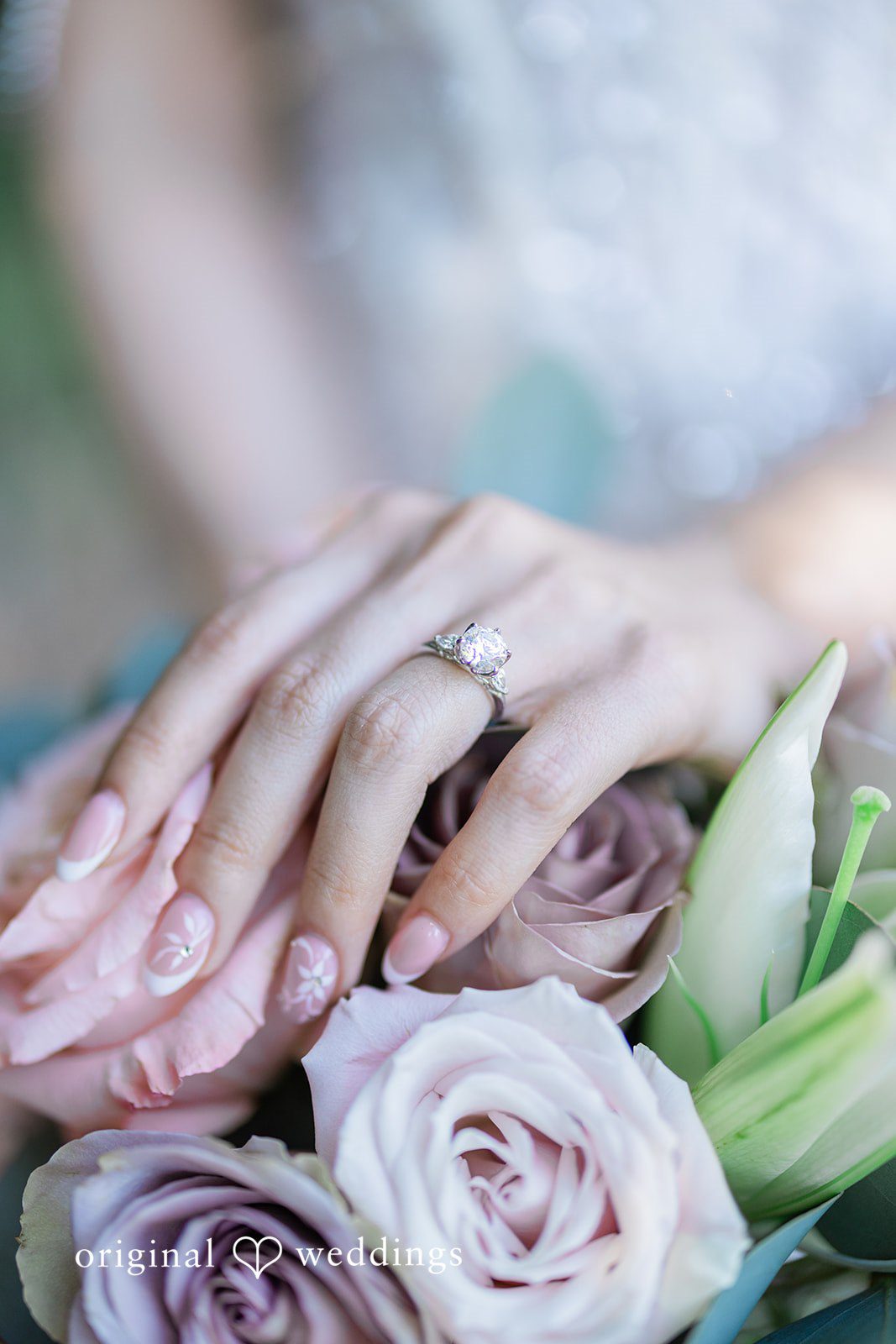 Veronica + Andrew A close-up view of a couple's hands displaying wedding rings over a bouquet of purple roses.
