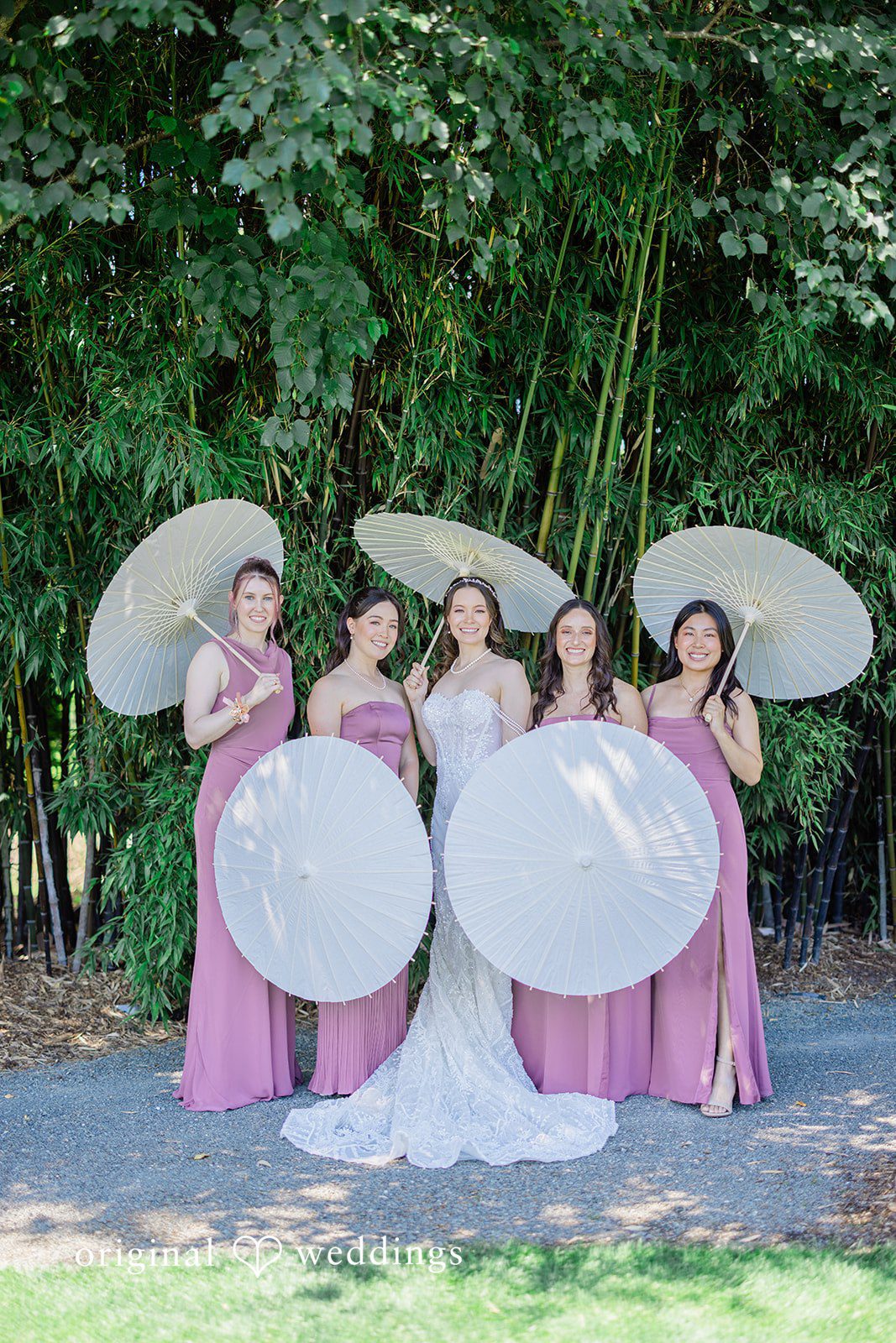 Veronica + Andrew A group of bridesmaids holding white parasols while posing together.