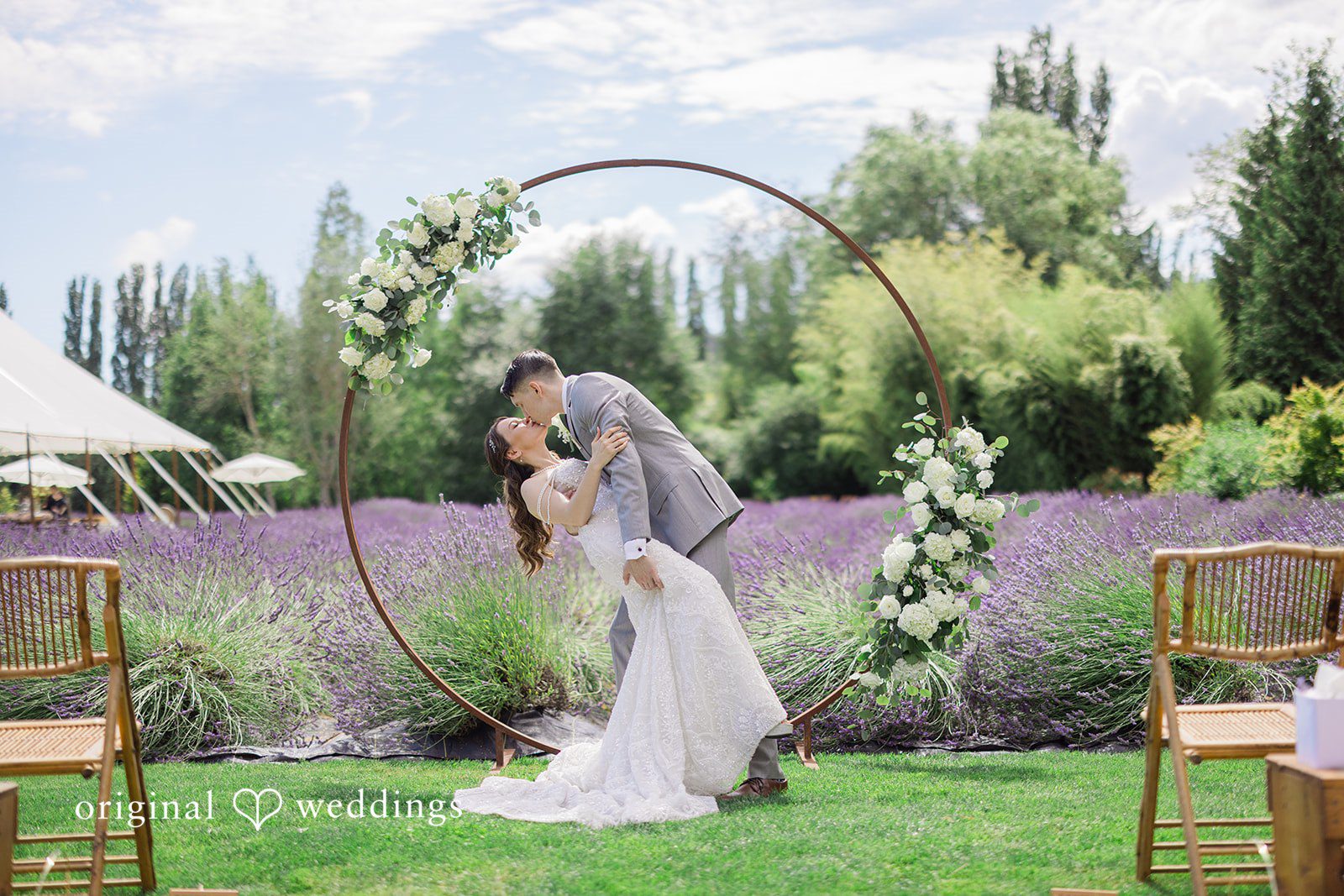 Veronica + Andrew A wedding couple shares a romantic kiss underneath a circular floral arch.