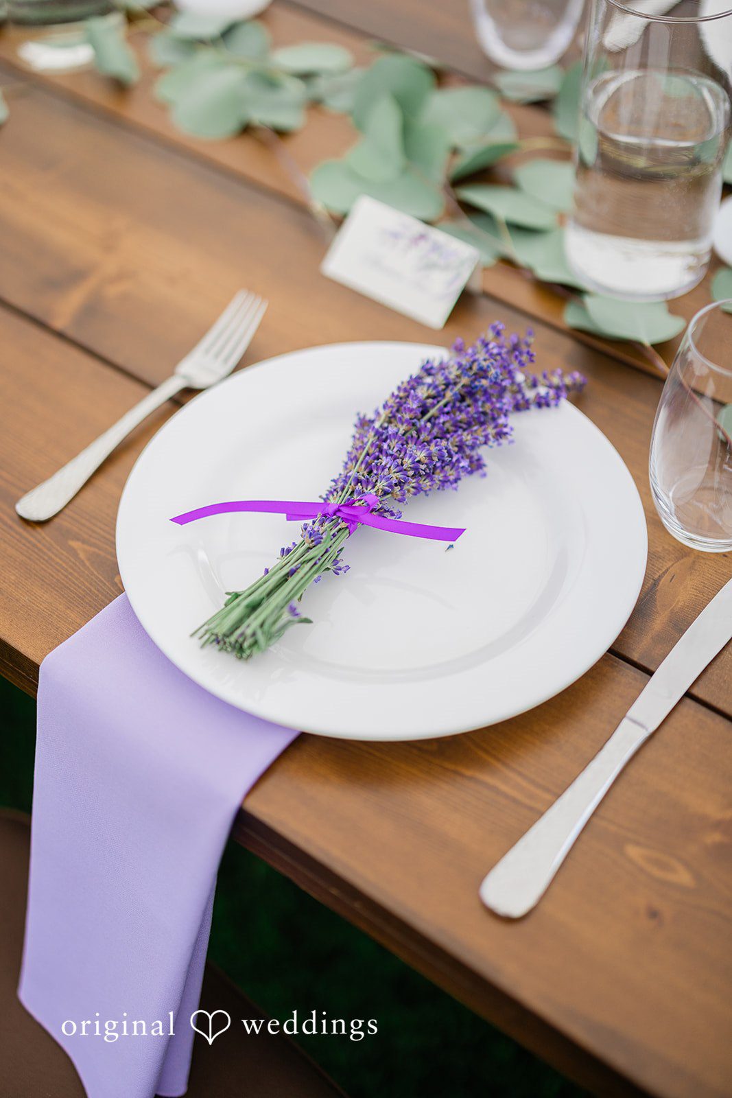 Veronica + Andrew A close-up view of a formal table setting featuring a white plate decorated with lavender stalks.