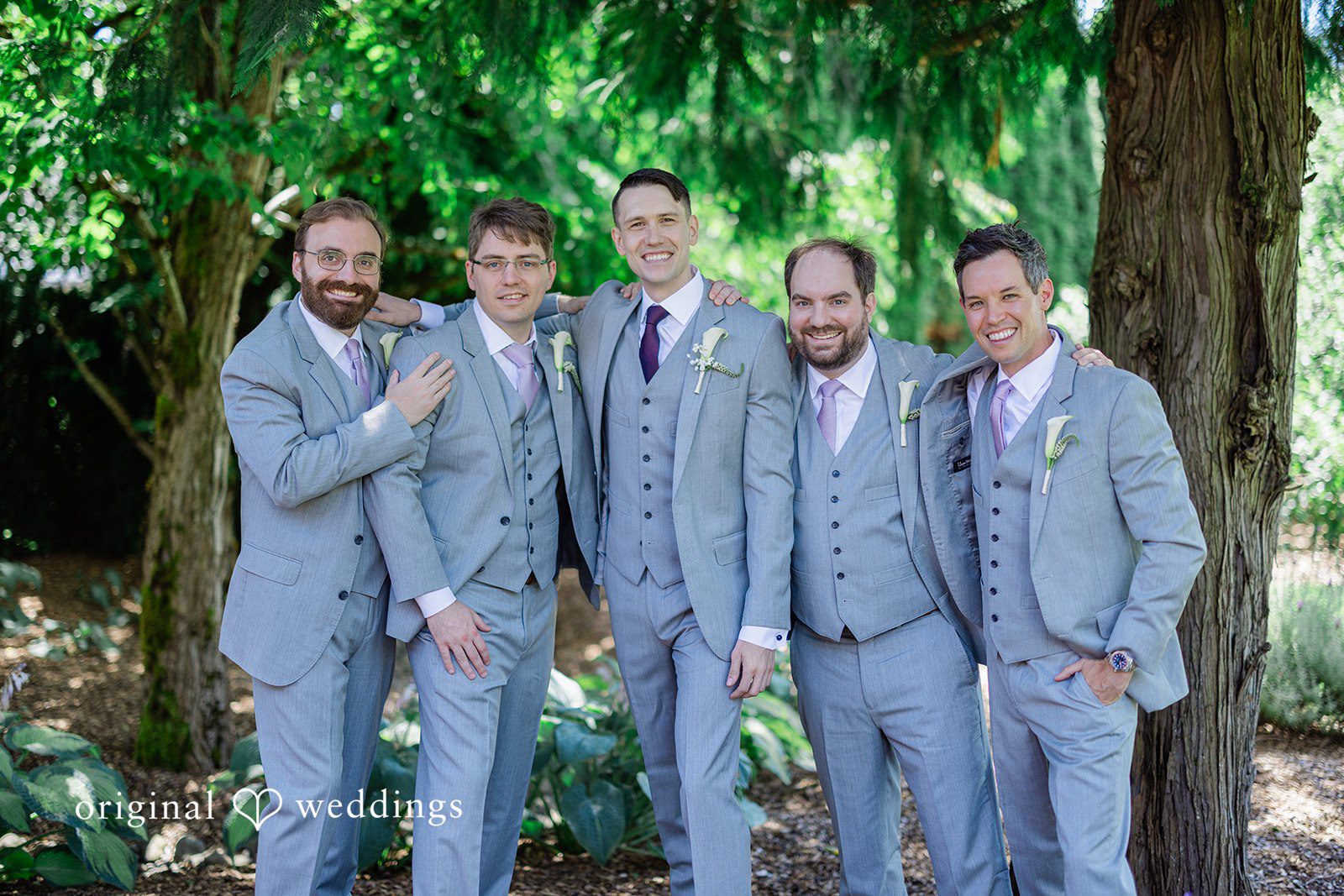 Veronica + Andrew A groom posing cheerfully alongside five groomsmen in matching grey suits