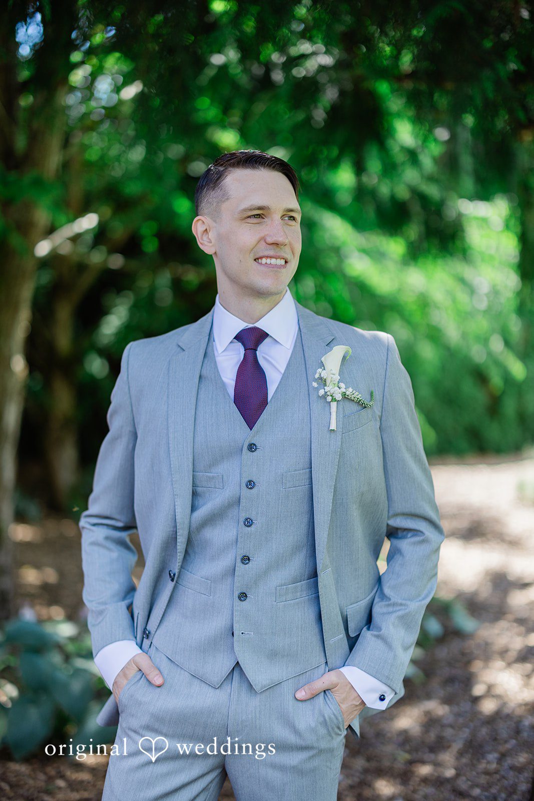 Veronica + Andrew A smiling groom posing solo in a grey three-piece suit.