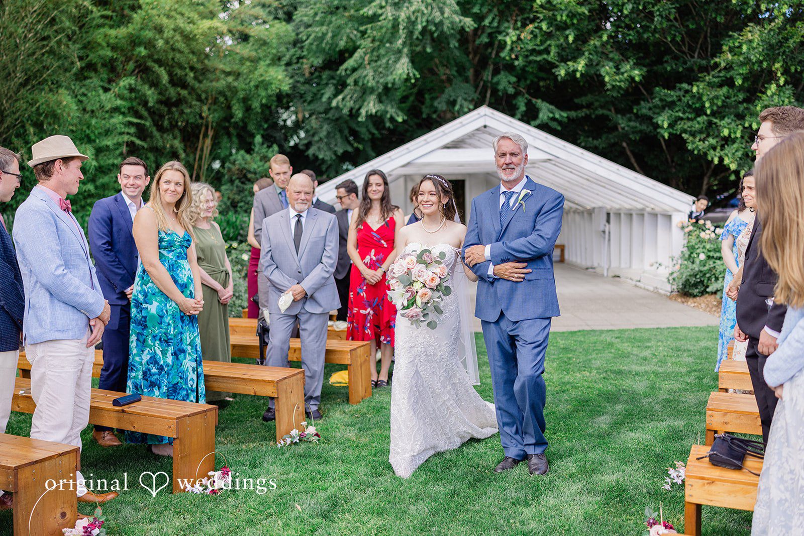 Veronica + Andrew A wedding ceremony in progress with guests seated on benches facing the couple.