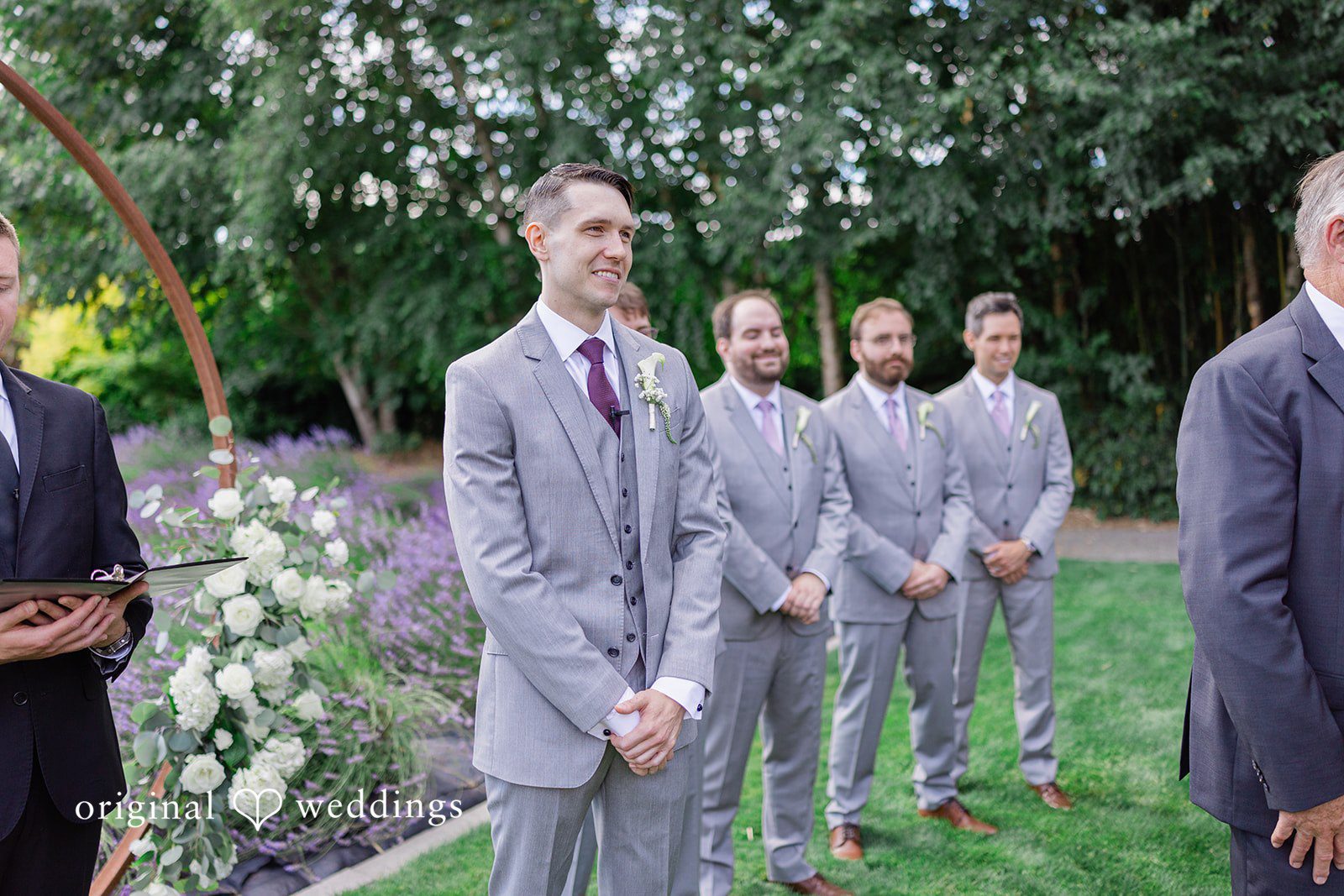 Veronica + Andrew A groom and his groomsmen standing in a formal line on a lawn.