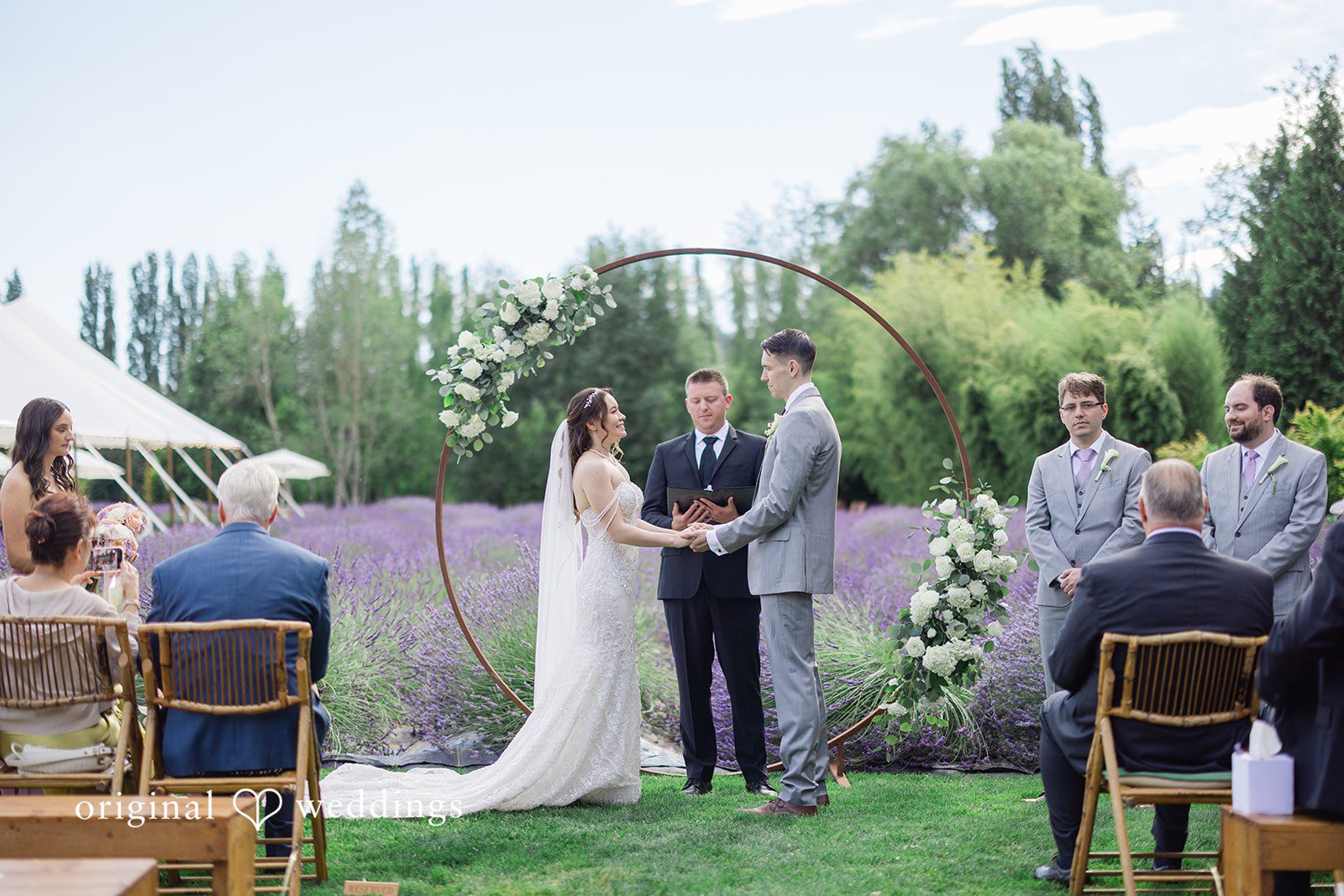 Veronica + Andrew A wedding couple exchanging vows in front of a scenic lavender field.