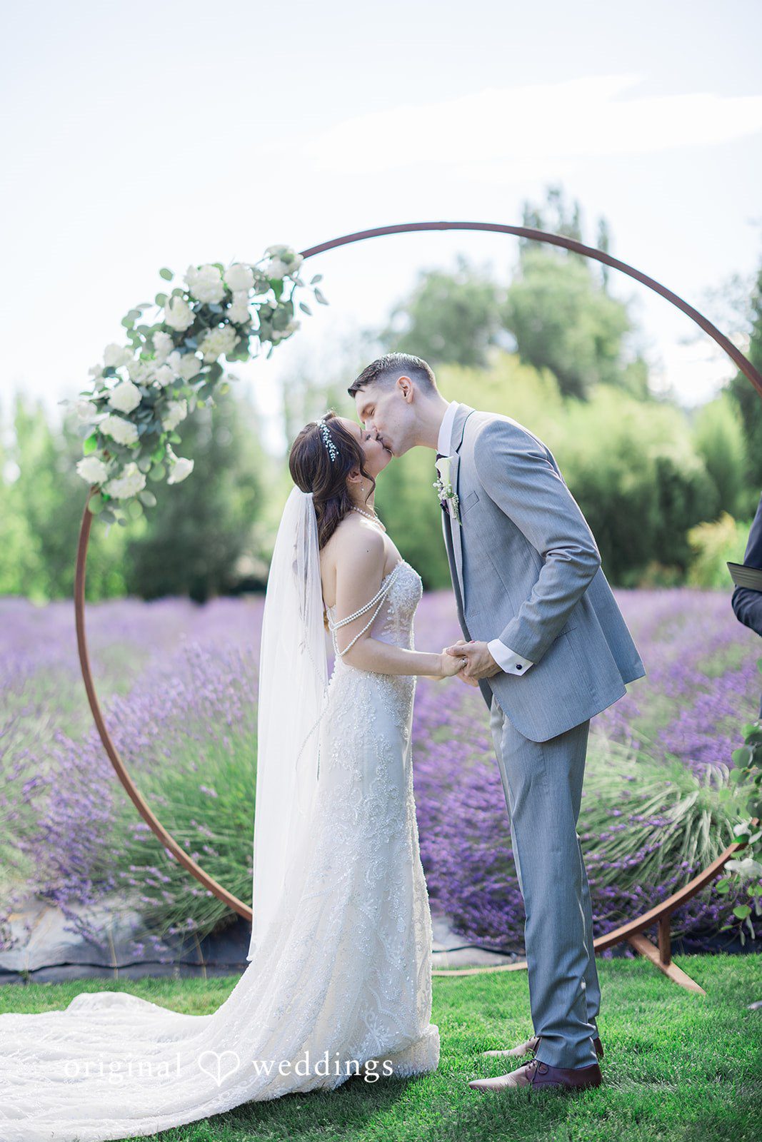 Veronica + Andrew A wedding couple sharing a kiss under a circular floral arch.