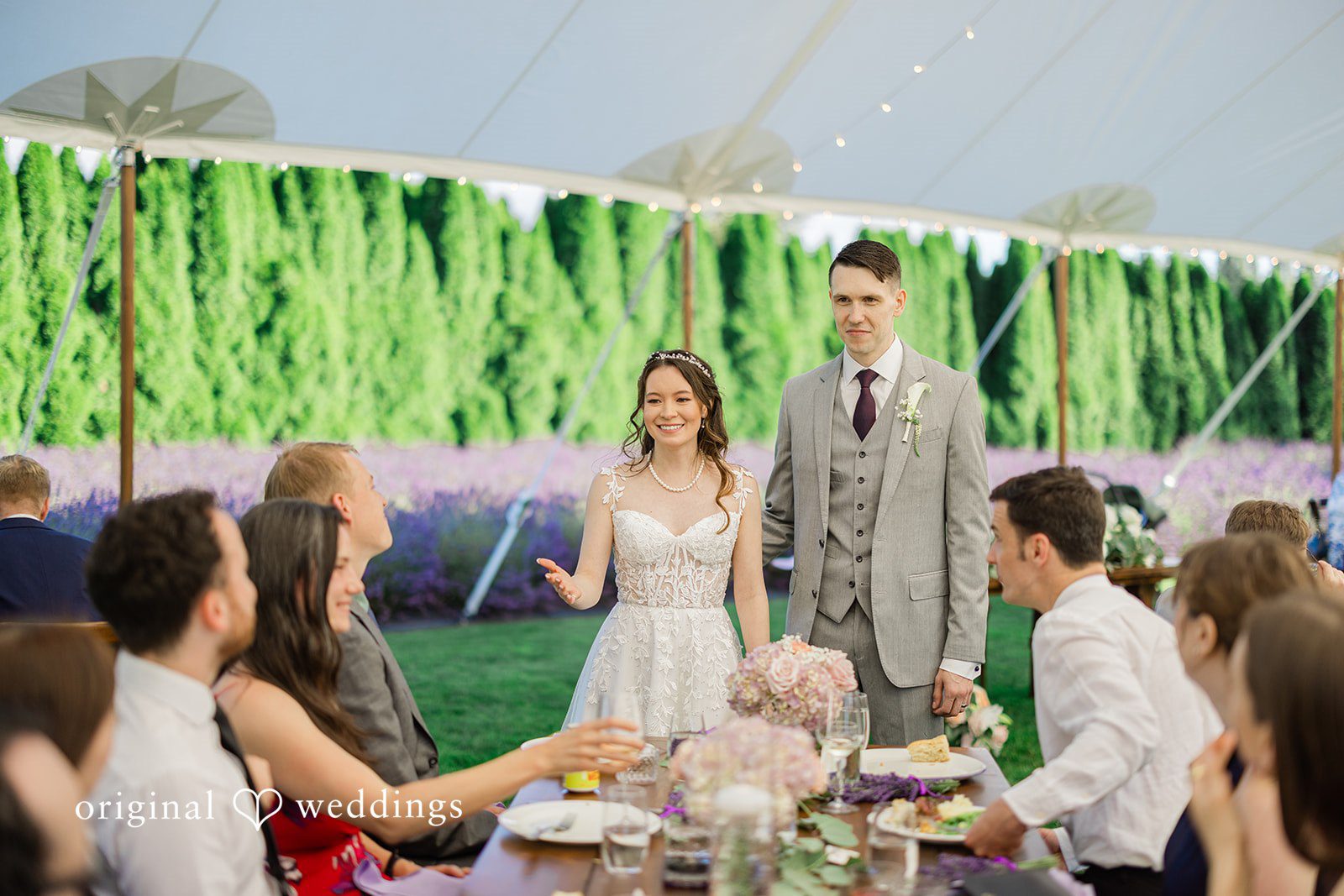 Veronica + Andrew A wedding couple stands and talks with guests seated at a reception table.