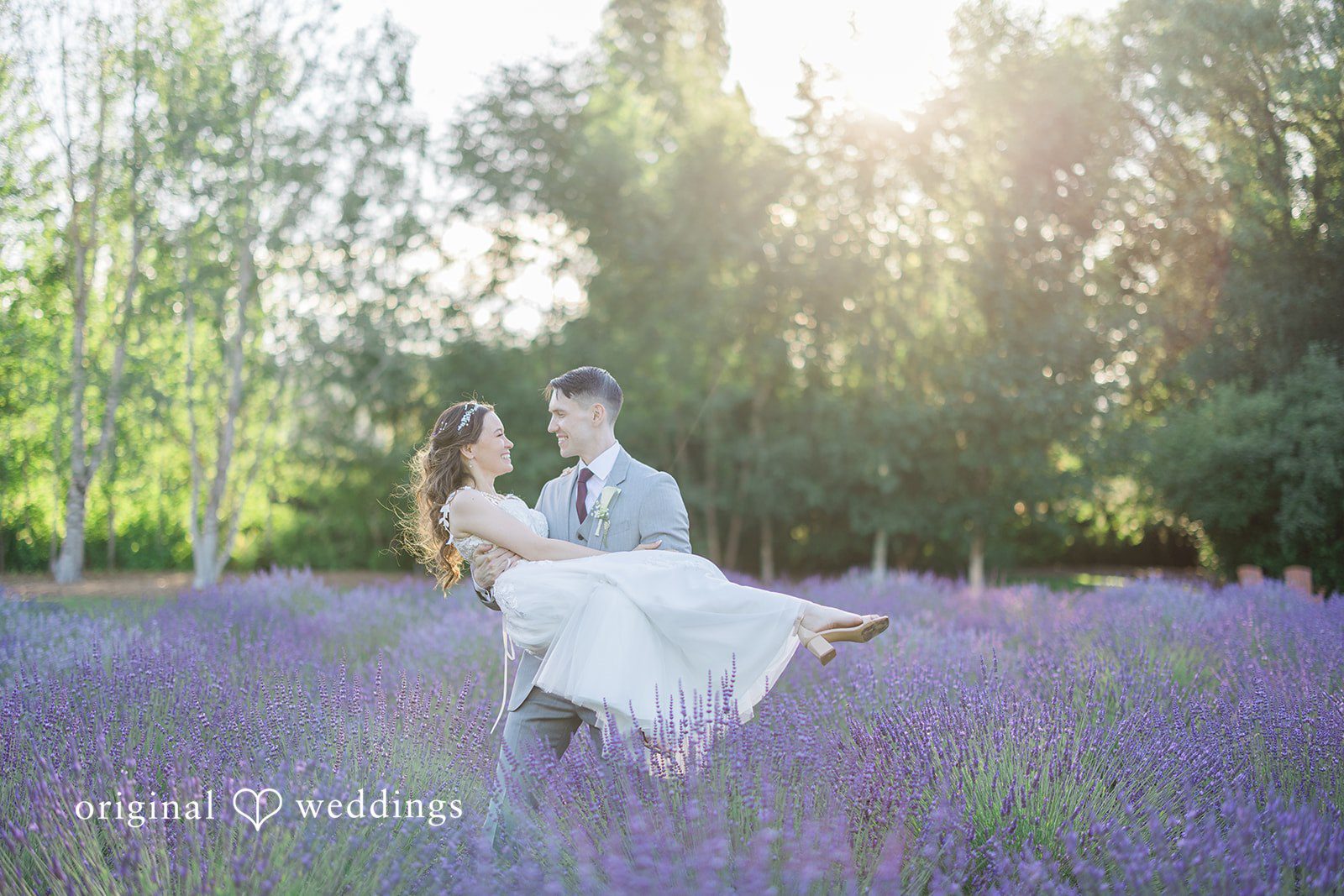 Veronica + Andrew A groom lifts and carries the bride through a vibrant purple lavender field.