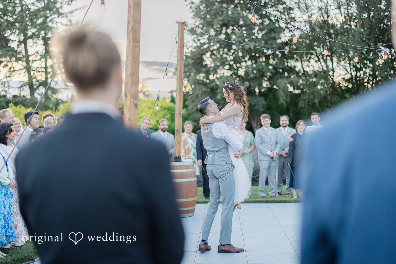 Veronica + Andrew A groom lifts the bride high into the air on a dance floor in front of guests.