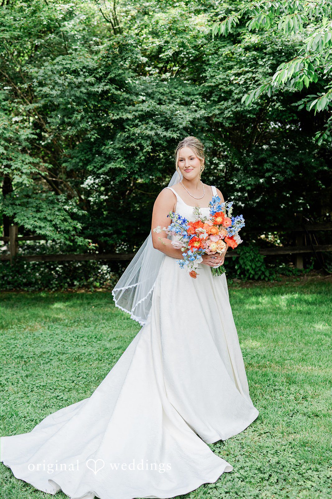 Katrina + Japhet Bride in a white gown holding a bouquet while walking across a green grass lawn.