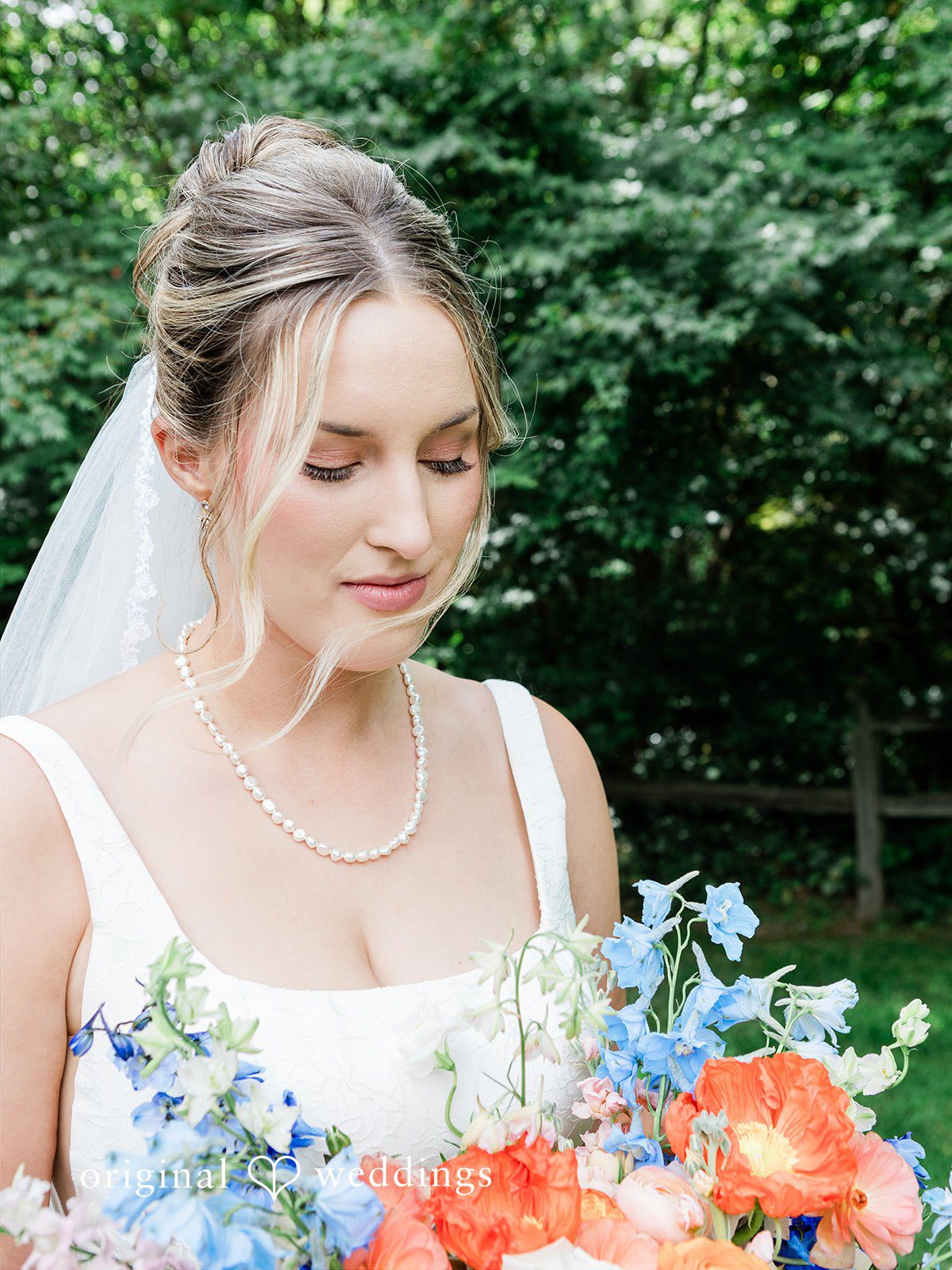 Katrina + Japhet Close-up portrait of a smiling bride looking down and holding her wedding bouquet.