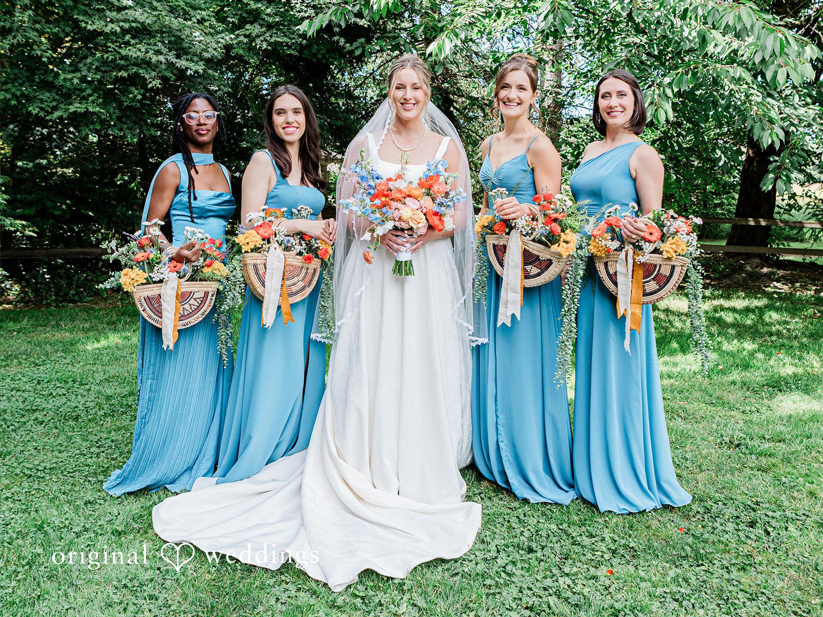 Katrina + Japhet Bride standing with four bridesmaids wearing matching light blue dresses in front of trees.