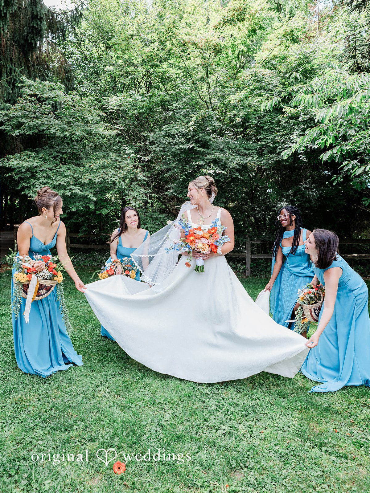 Katrina + Japhet Group of bridesmaids in blue dresses helping to adjust the bride's long dress train.