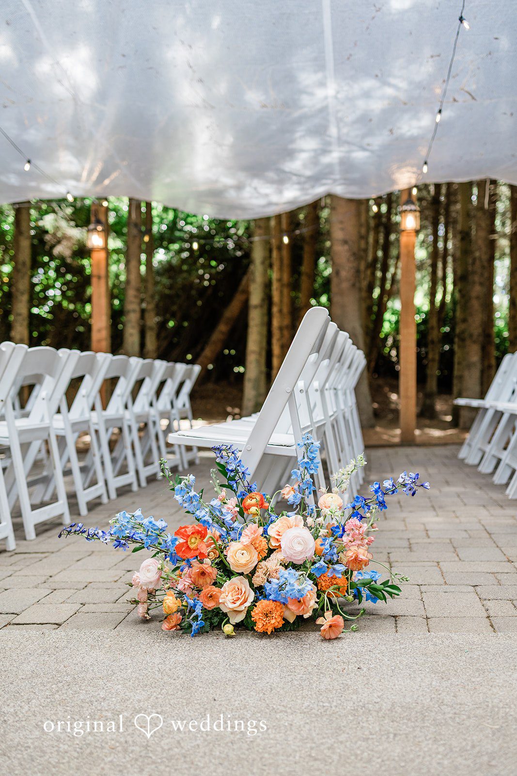 Katrina + Japhet Vibrant arrangement of blue, orange, and peach flowers placed on a paved reception ground.