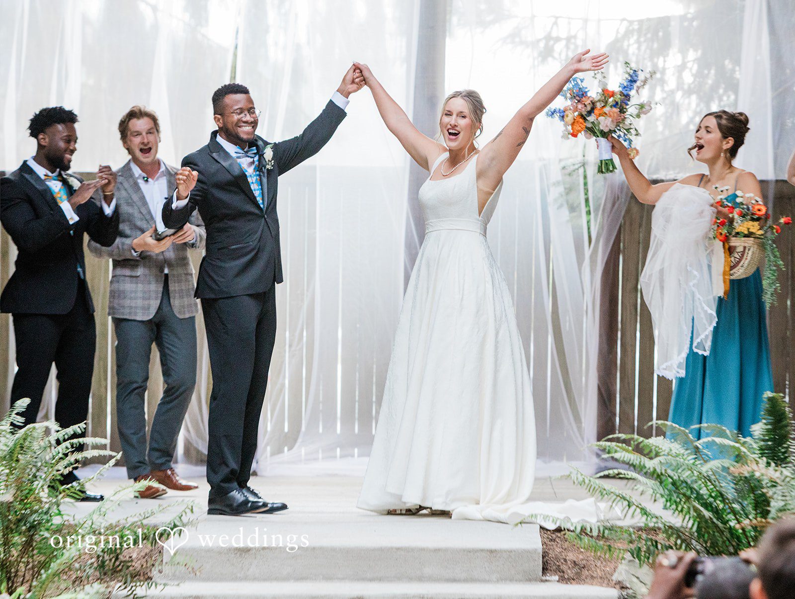 Katrina + Japhet Bride and groom raising their hands in celebration at the altar as guests cheer.