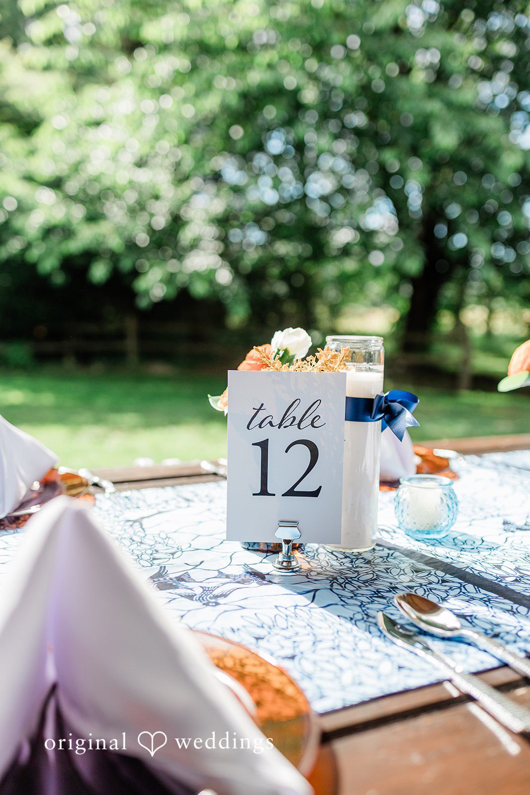 Katrina + Japhet Detailed view of a wedding reception centerpiece featuring table number twelve surrounded by decorations.