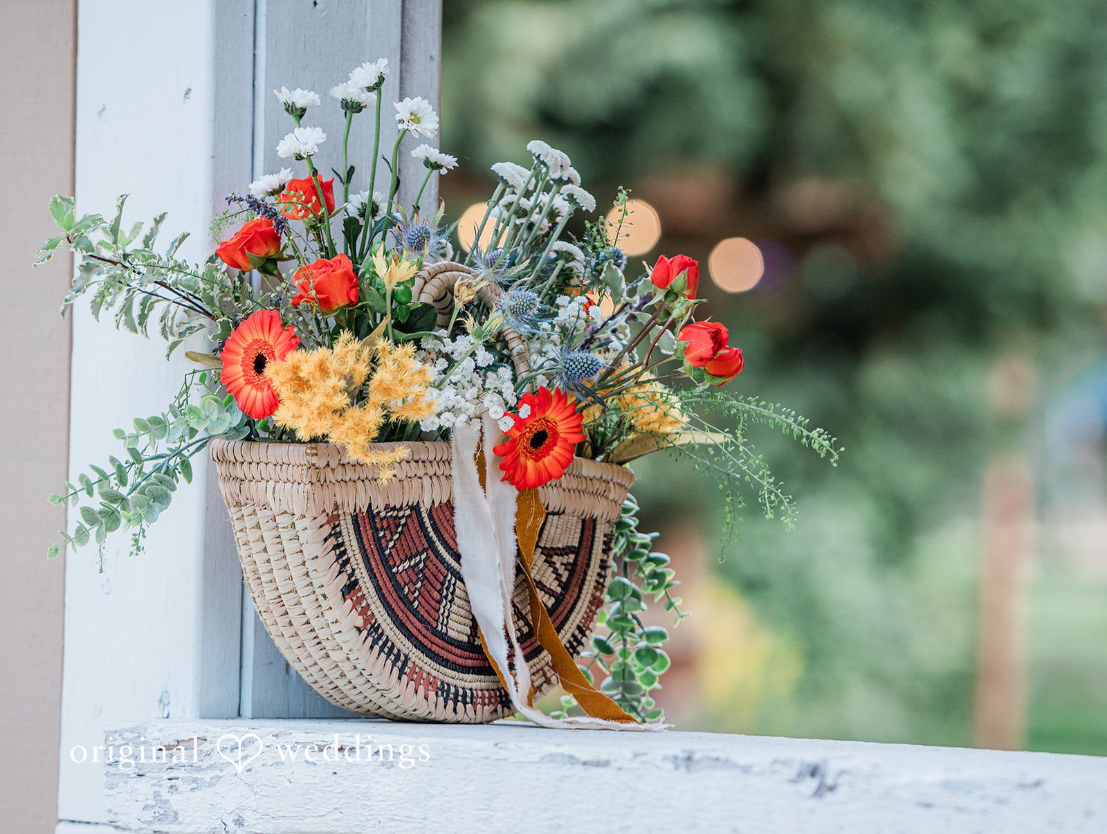Katrina + Japhet Bright wedding bouquet with red, orange, and blue flowers hanging from a wooden post.