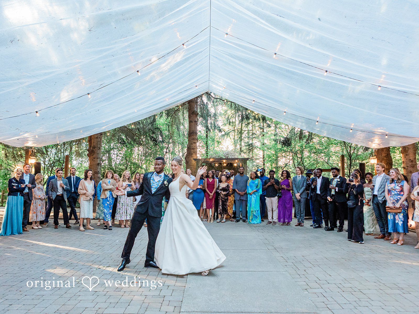 Katrina + Japhet Bride and groom dancing into a wedding reception venue under a white tent canopy.