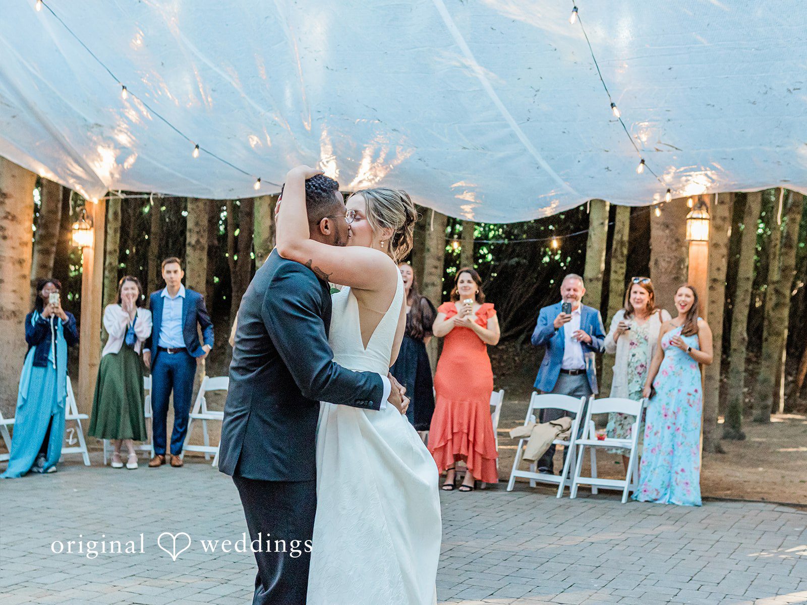 Katrina + Japhet Bride and groom slow dancing close together under string lights during the reception.