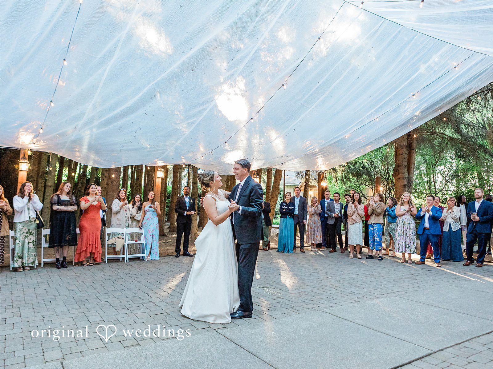Katrina + Japhet Wide shot of the bride and groom dancing in the center of the floor beneath a large white canopy.
