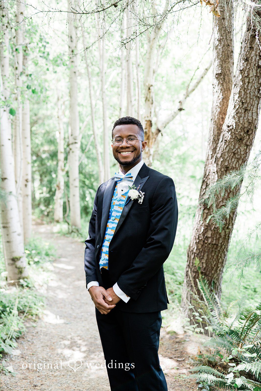 Katrina + Japhet Groom in a dark suit smiling happily while standing in a wooded forest area.