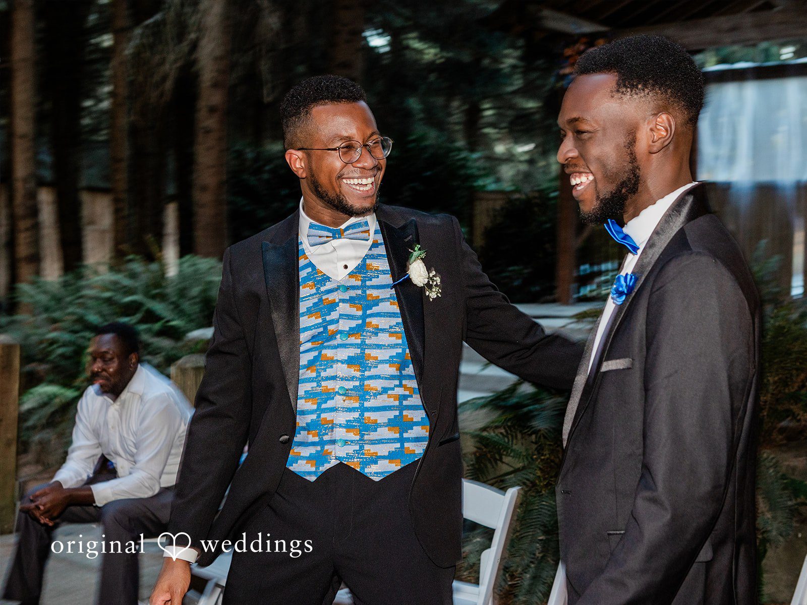 Katrina + Japhet Groom smiling and talking with a groomsman in a dark suit during the evening reception.