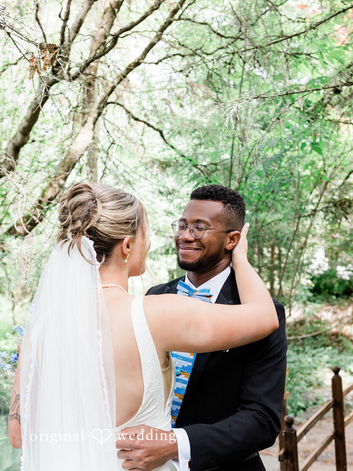 Katrina + Japhet Bride and groom sharing an affectionate embrace while surrounded by lush green trees.