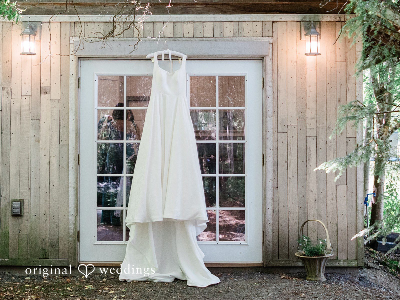 Katrina + Japhet White lace wedding gown hanging elegantly from a glass-paned double door.
