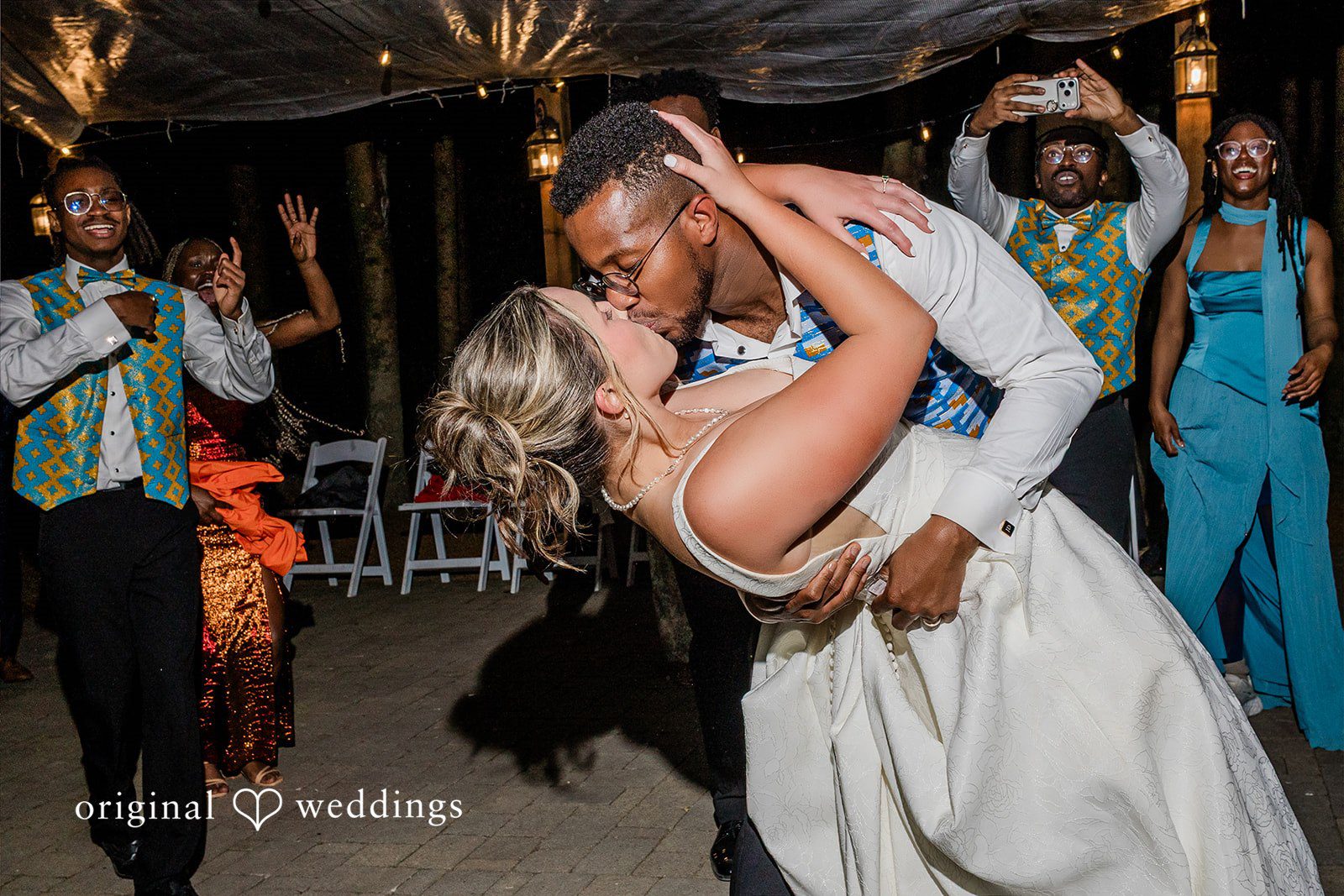 Katrina + Japhet Groom dipping the bride low to the ground and kissing her during a lively dance celebration.