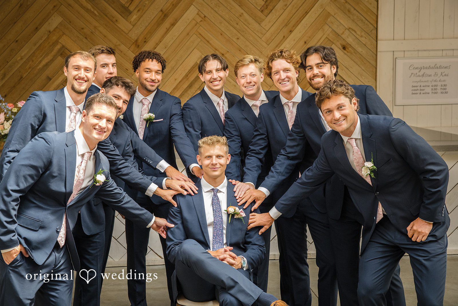 A groom and his groomsmen in dark suits share a playful moment while posing together.