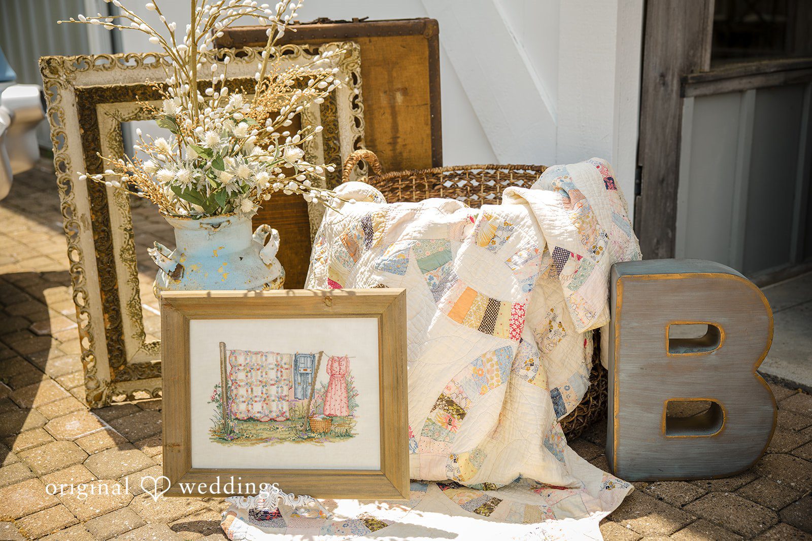 A rustic wedding display features framed artwork, decorative wooden blocks, and a patterned cloth.