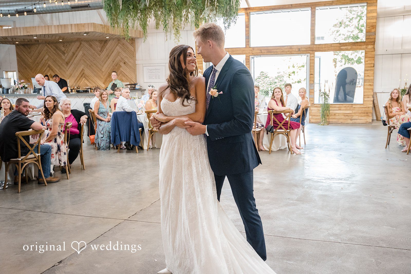 A bride and groom share a slow dance on the floor during their reception.