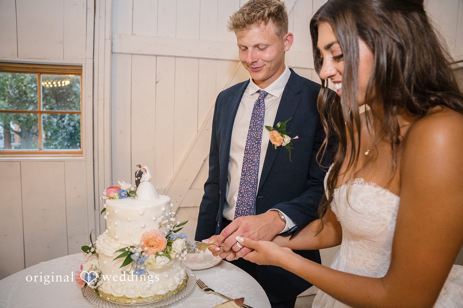 A groom and bride cuts a multi-tiered white wedding cake