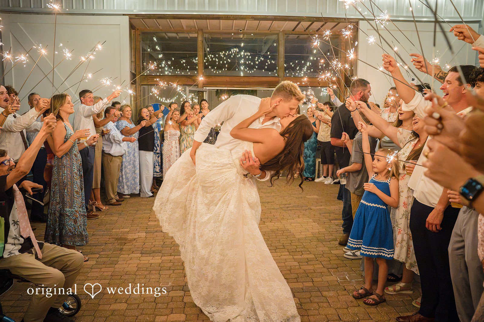 A bride moves down an aisle created by wedding guests cheering and holding up sparklers.