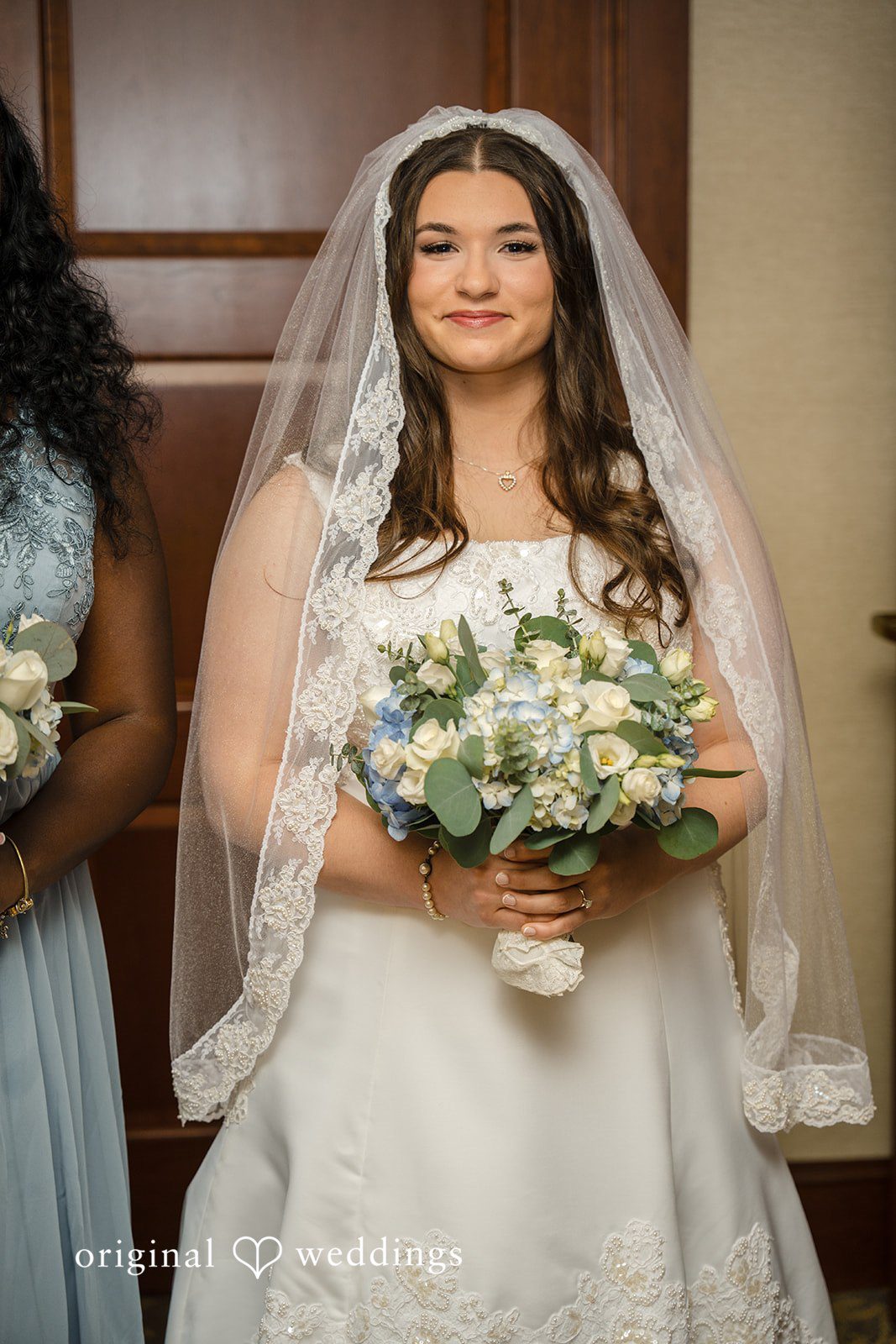 Ava + Zach A smiling bride in her gown holding a bouquet of white flowers.