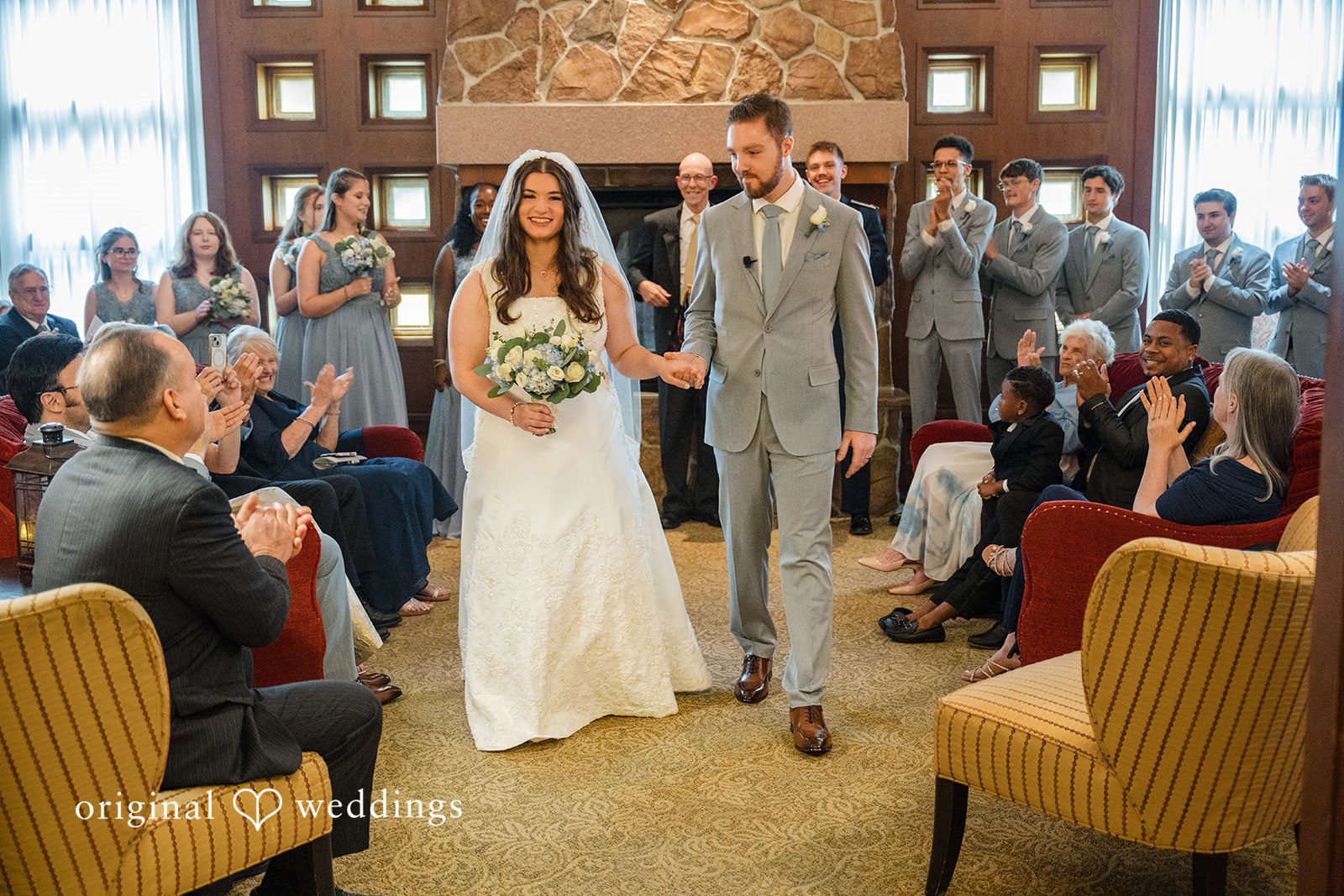 Ava + Zach A bride walking down the aisle towards the groom surrounded by seated guests.
