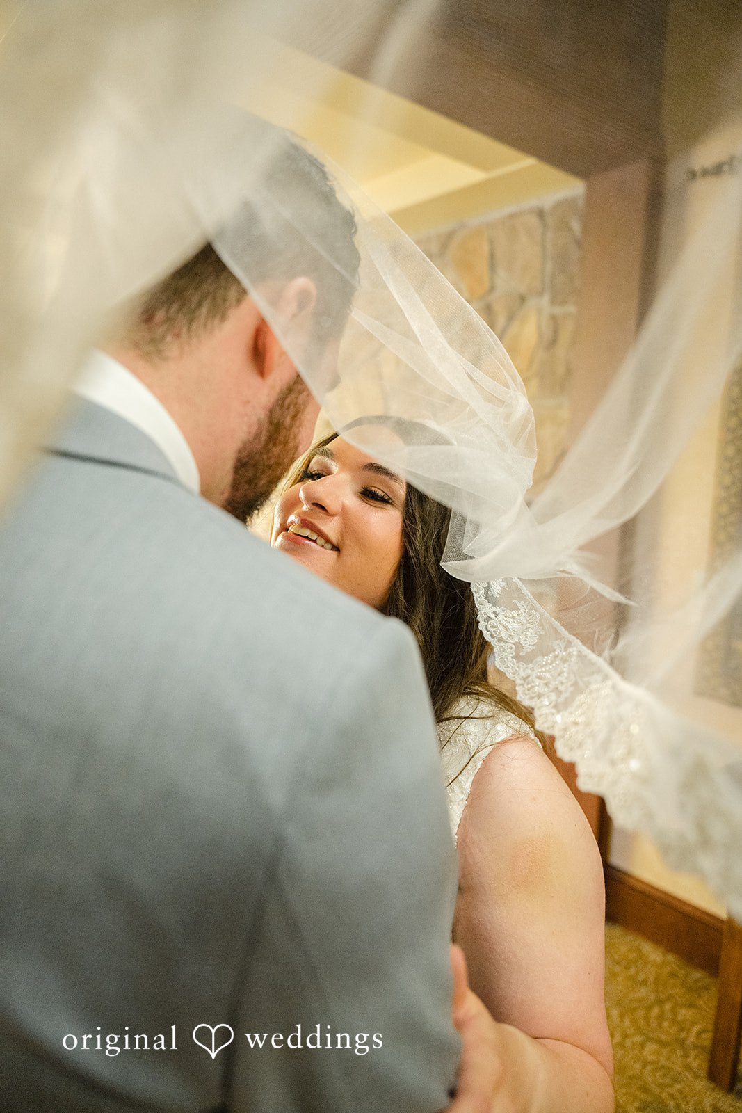 Ava + Zach A close-up of a bride and groom embracing under a flowing wedding veil.