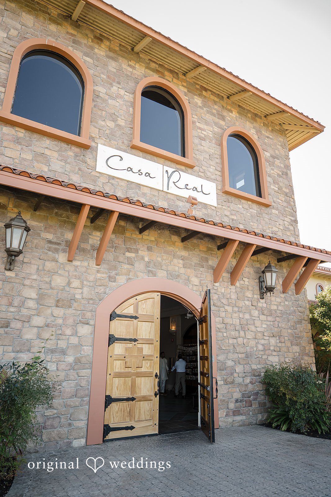 Kathir + Nandita A stone building featuring a rustic arched wooden entrance door.