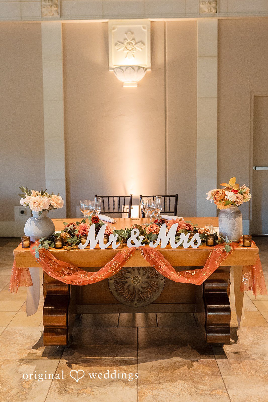 Kathir + Nandita A decorated wedding reception sweetheart table under warm lighting.