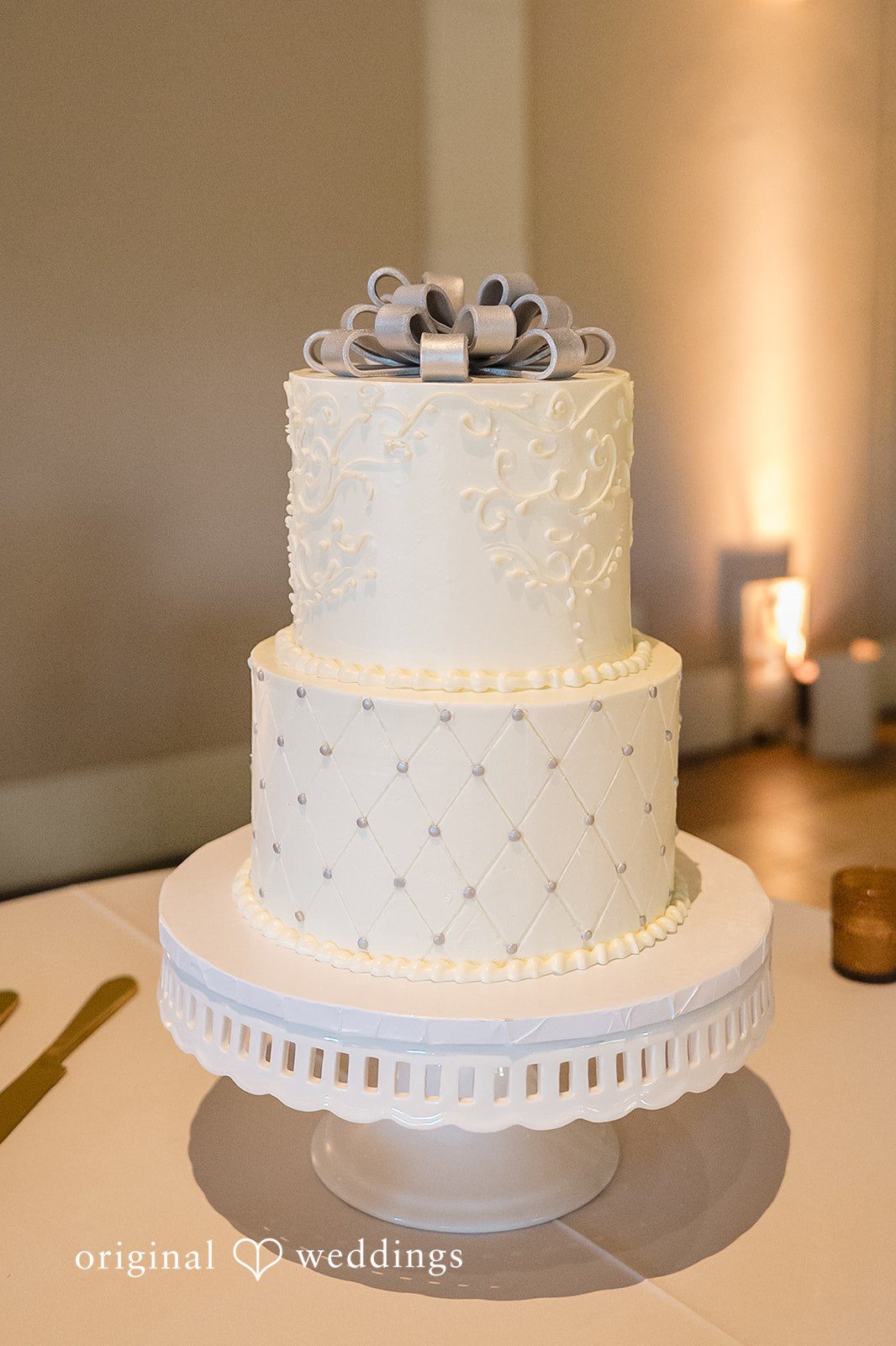 Kathir + Nandita A three-tiered white wedding cake displayed on a round stand.