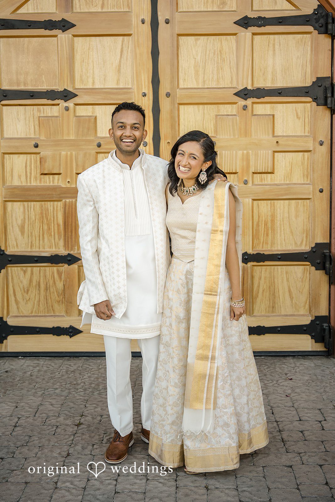 Kathir + Nandita A bride and groom posing closely in matching white and gold wedding attire.