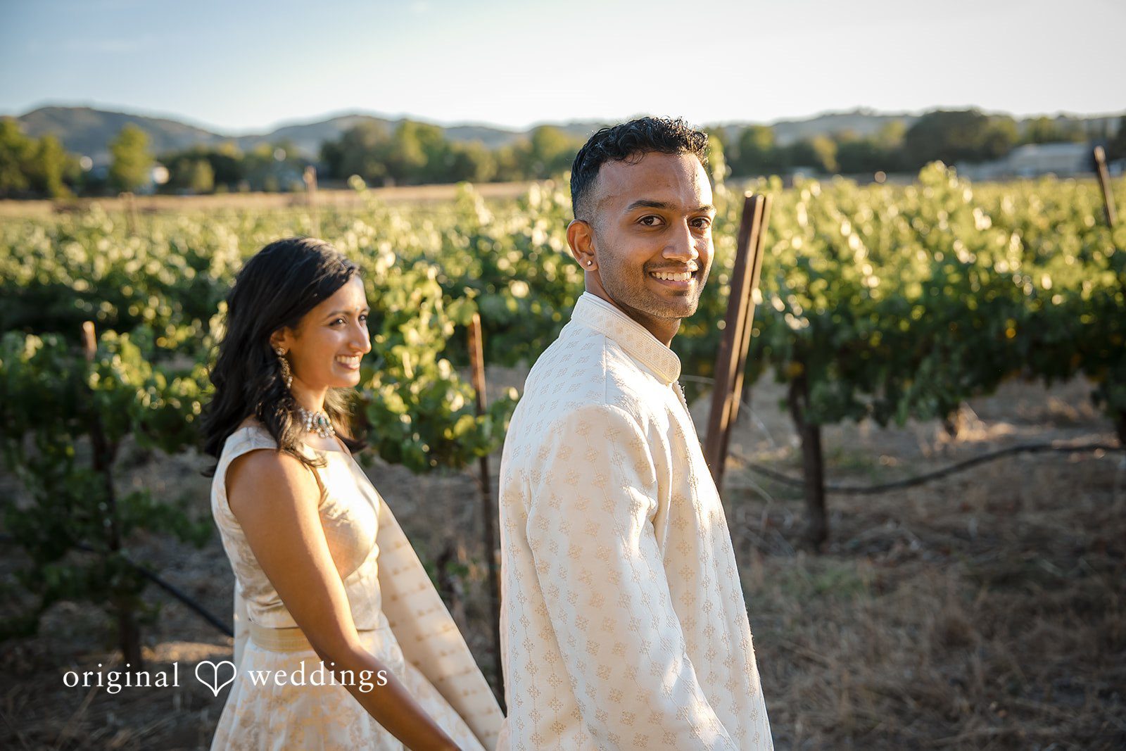 Kathir + Nandita A bride and groom standing side-by-side among rows of grapevines.