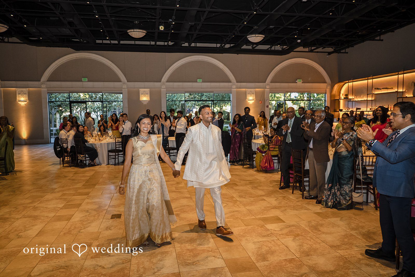 Kathir + Nandita A bride and groom dancing together in the center of a spacious ballroom floor.