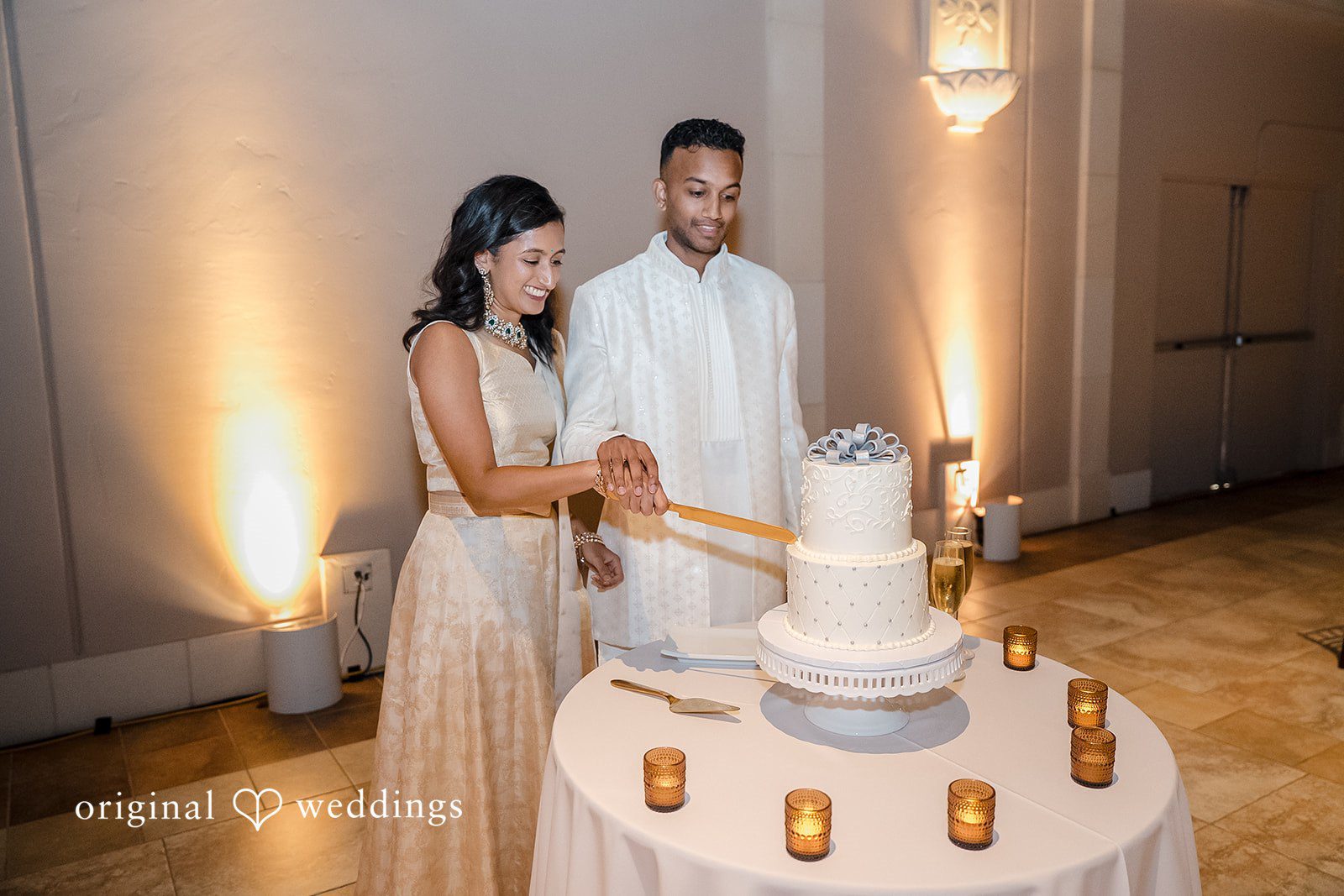 Kathir + Nandita A bride and groom preparing to cut their tiered white wedding cake.