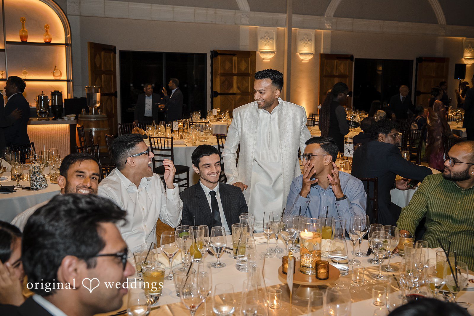 Kathir + Nandita Guests seated around a banquet table chatting during a wedding dinner.
