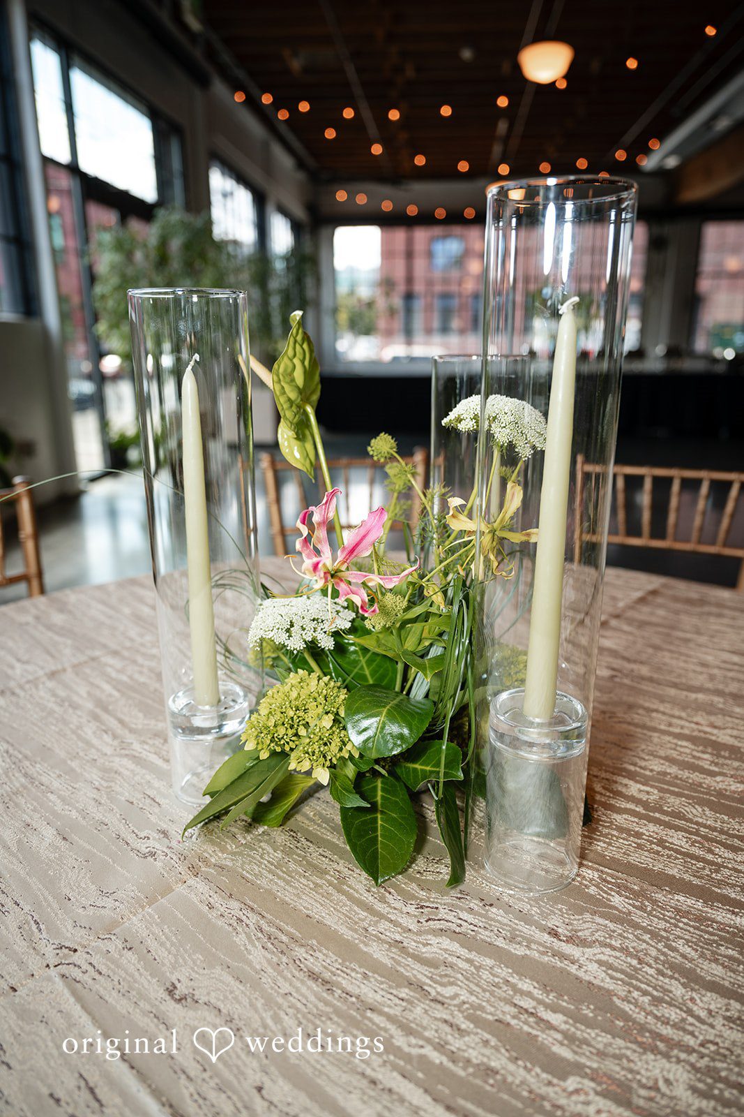 A clear acrylic structure decorated with green vines and white flowers on a wooden floor.