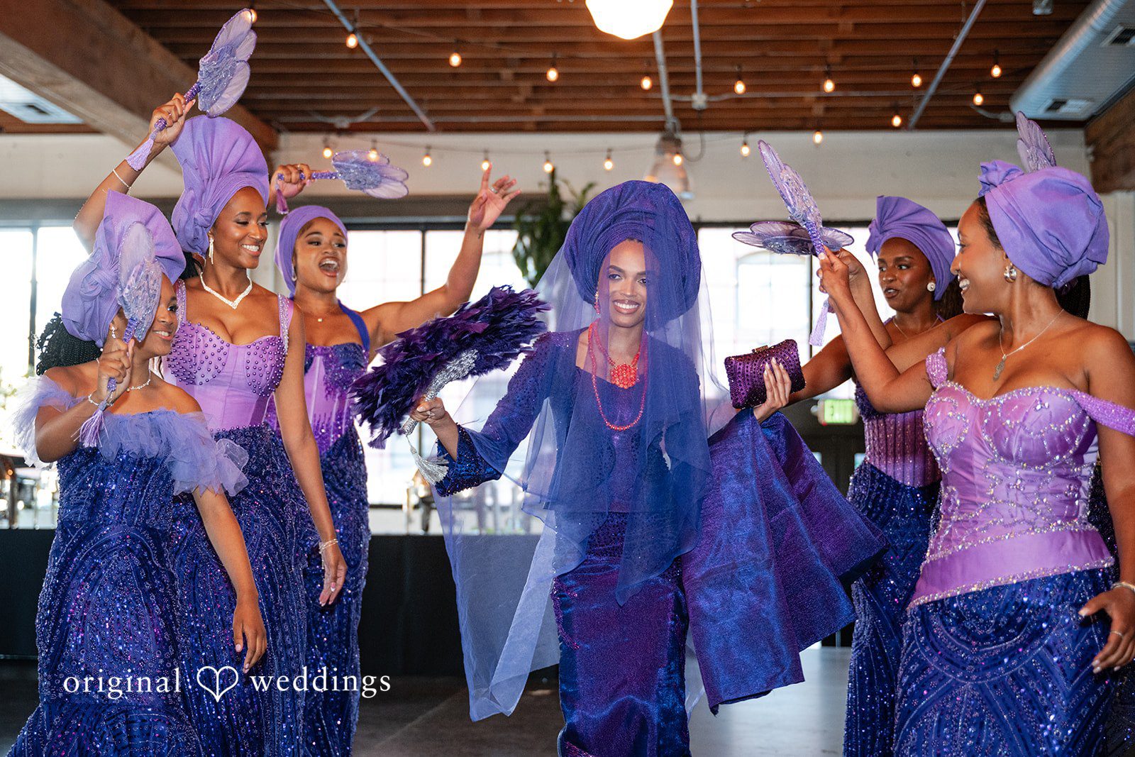 A group of bridesmaids in vibrant blue and purple dresses smiling together.